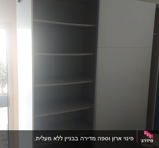 ארון פתוח עם מדפים ריקים ובגדים על המיטה